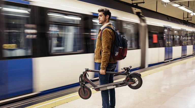 Homme portant une trottinette électrique pliable dans le métro