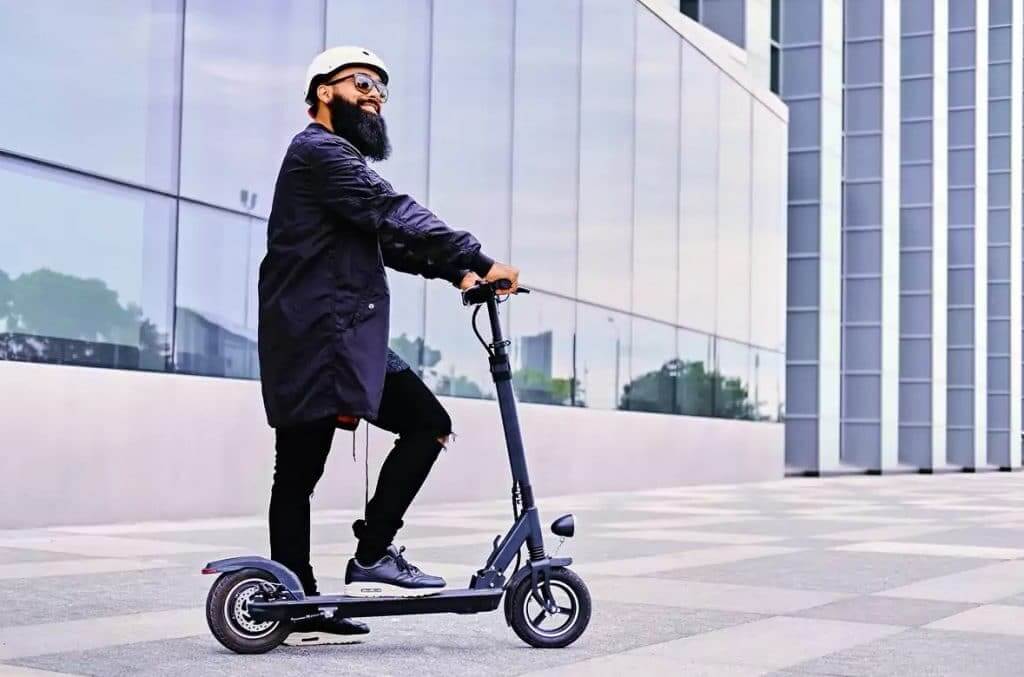 Homme de grande taille sur une trottinette électrique en milieu urbain