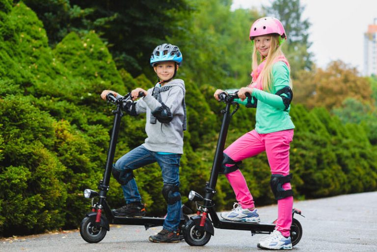Deux enfants en trottinette électrique dans un parc urbain, casque et équipement de sécurité